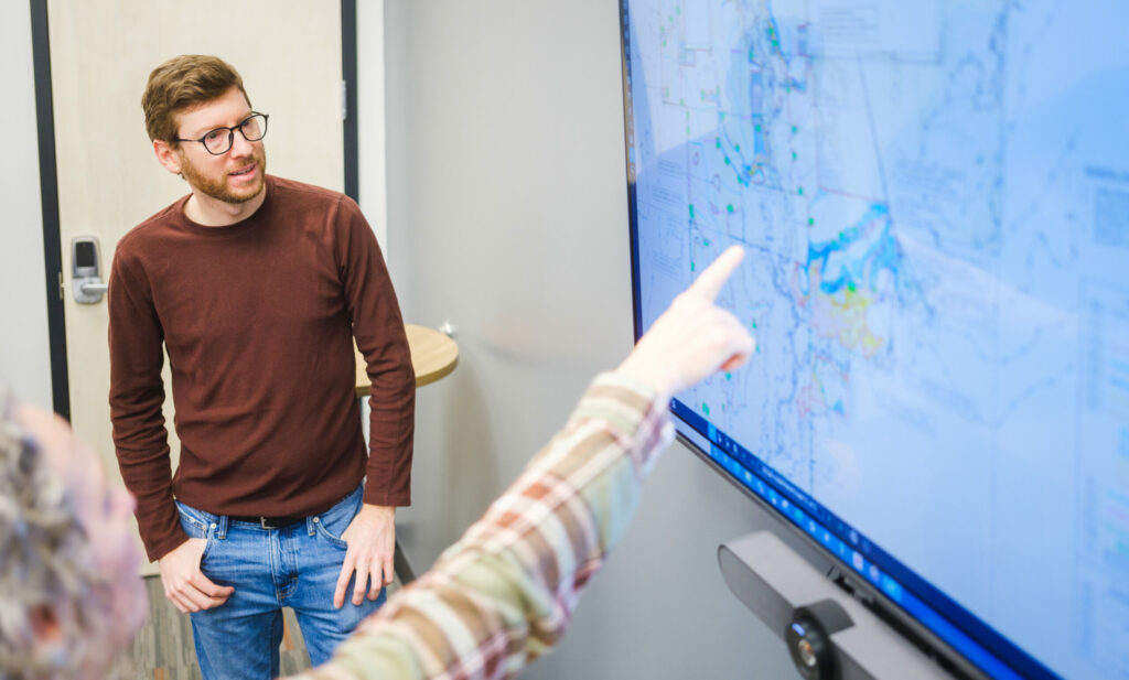 Someone pointing at engineering drawings on a screen